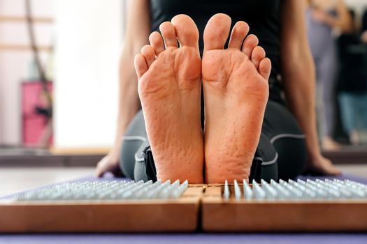 Feet and wooden board with sharp metal nails. Sadhu foot board. Yoga relaxation practice training tool.