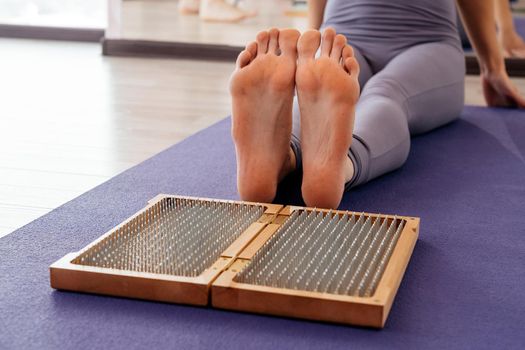 Feet and wooden board with sharp metal nails. Sadhu foot board. Yoga relaxation practice training tool.