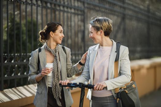 A two successful businesswomen having a quick coffee break and chatting while walking through the city.