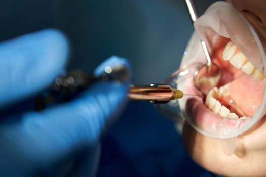 Patient visiting a dental office. Adult woman sitting in chair. Dentist hands in rubber protective gloves. Receiving anesthesia by syringe