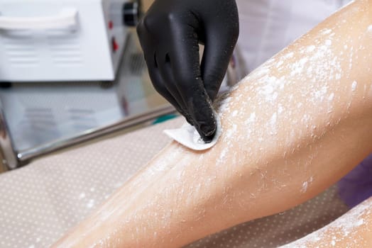 Beautician getting ready to wax female legs in spa center