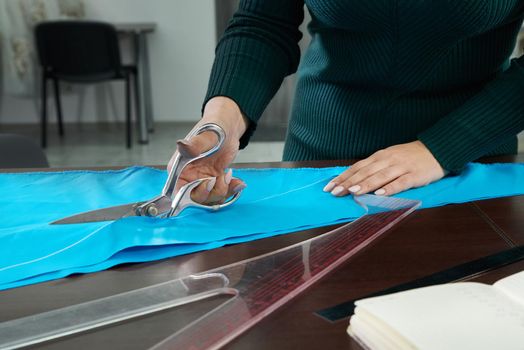 Dressmaker cutting fabric in atelier shop