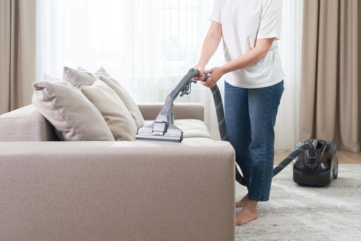Housewife Cleaning Sofa With a Vacuum Cleaner