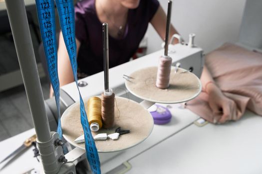 Woman using sewing machine in tailor studio or modern atelier shop