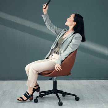 Selfie, video call and woman with a phone for connection, internet and communication at work on a chair. Corporate and Asian employee reading an email, message or chat on a mobile app in an office.