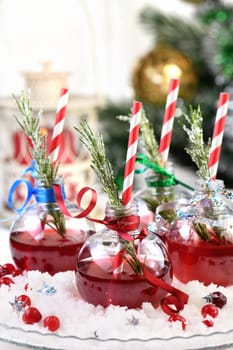 Gin with tonic and cranberry juice. The cocktail is full of festive Christmas flavors. Served in transparent bowls with a branch of rosemary.