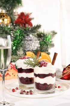 Christmas cranberry dessert tiramisu with mascarpone and whipped cream, chocolate biscuit crumble and cranberry jam, garnished with orange slices, candied cranberries and rosemary.