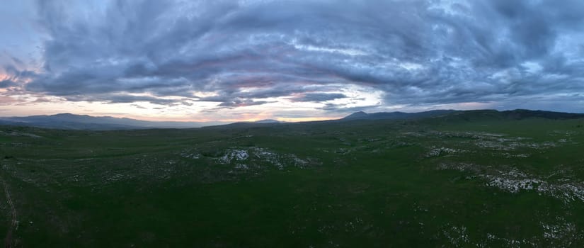 Aerial view of countryside landscape. Clouds with shades of purple, orange and green vegetation. Dramatic sky. High quality stock photo