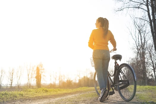 Girl on a bike in the countryside in sunrise time. Copy space