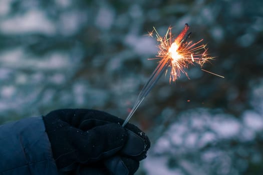 Burning Sparklers in a Hand Outdoors in Winter in Evening. New Year Celebration Party