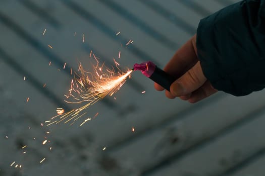 Burning Firecracker with Sparks. Guy Holding a Petard in a Hand. Loud and Dangerous New Year's Entertainment. Hooliganism with Pyrotechnics. Noise of Firecrackers in Public Places