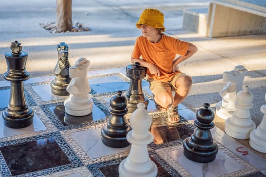 Father and son playing chess spending time together outdoor. Kid play chess.