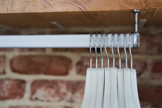 Many wooden white hangers on a rod. Store concept, sale, design, empty hanger. High quality photo