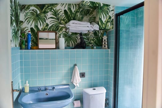 Stylish bathroom interior in blue. Wallpaper with ferns on the wall. High quality photo