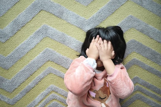 a upset child girl cover her face with hand .