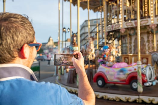 Father takes photos and videos of his daughter on the carousel on the phone