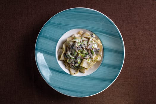 top view pasta with mushrooms and sauce in a blue plate.