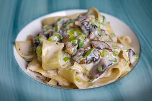 close-up of pasta with mushrooms and sauce in a blue plate.