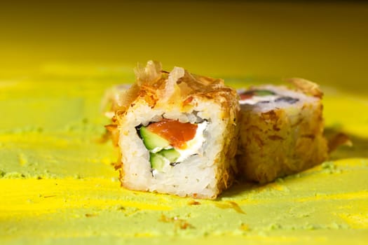 japanese cuisine rolls with fish, cucumber and cheese on a yellow background.