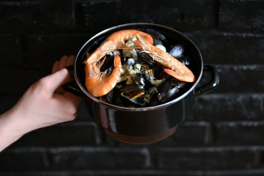 Mussels with sauce and shrimps on a black background