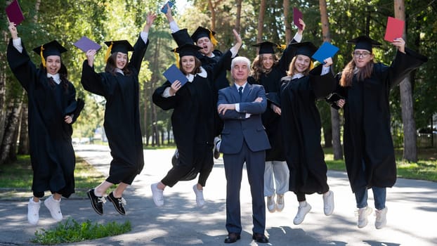 A university professor and seven robed graduates are jumping outdoors