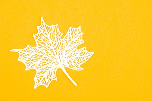 Carve of white paper maple leaves on a yellow background.