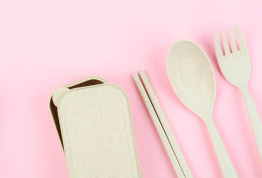 Plastic spoons, forks and chopsticks set on pink color background.