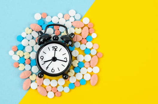 Alarm clock and many drug on a yellow background. Taking medicine at the right time concepts.