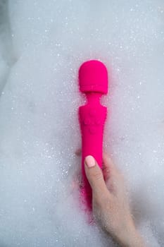 Woman lies in a bubble bath and uses a vibrator