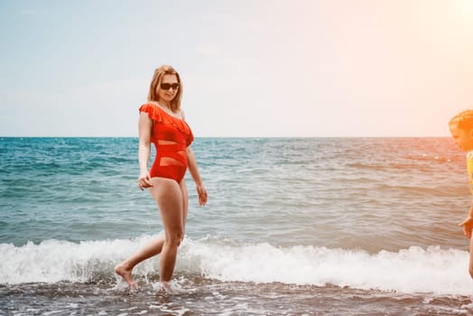 Happy loving family mother and daughter having fun together on the beach. Mum playing with her kid in holiday vacation next to the ocean - Family lifestyle and love concept.