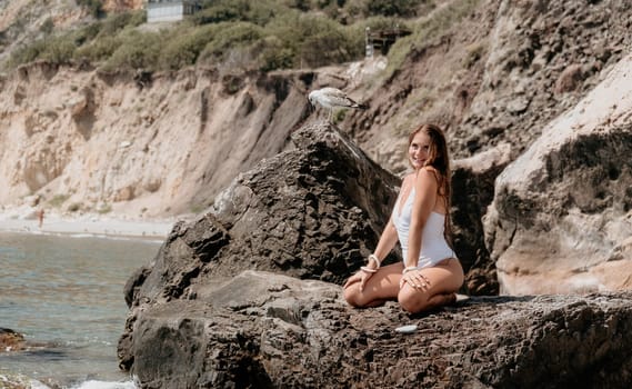 Woman travel sea. Young Happy woman in a long red dress posing on a beach near the sea on background of volcanic rocks, like in Iceland, sharing travel adventure journey