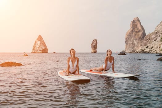 Woman sup yoga. Middle age sporty woman practising yoga pilates on paddle sup surfboard. Female stretching doing workout on sea water. Modern individual hipster outdoor summer sport activity