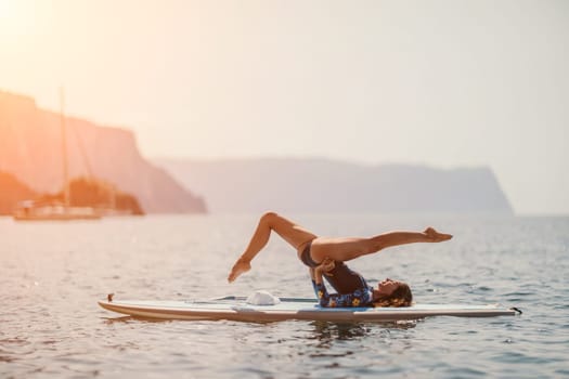 Woman sup yoga. Middle age sporty woman practising yoga pilates on paddle sup surfboard. Female stretching doing workout on sea water. Modern individual hipster outdoor summer sport activity