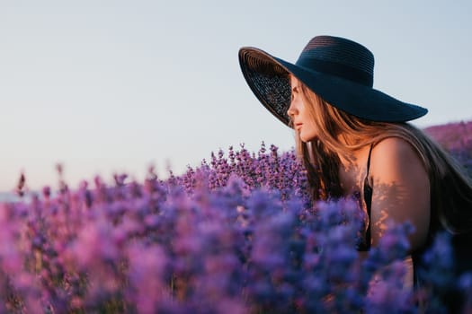 Close up portrait of young beautiful woman in a white dress and a hat is walking in the lavender field and smelling lavender bouquet.