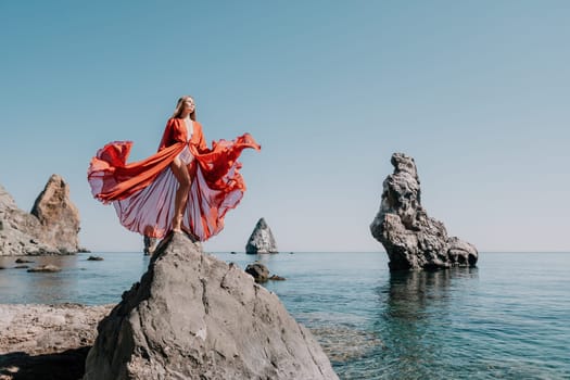 Woman travel sea. Happy tourist taking picture outdoors for memories. Woman traveler looks at the edge of the cliff on the sea bay of mountains, sharing travel adventure journey.