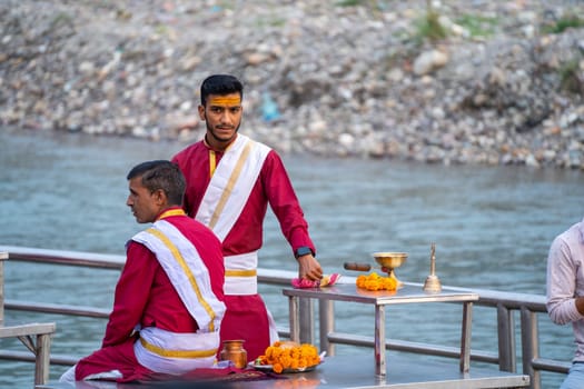 Rishikesh, Uttarakhand - circa 2023 : Group of priests preparing for the evening ganga aarti ceremony discussing the plan with their guru teacher who wears white on red