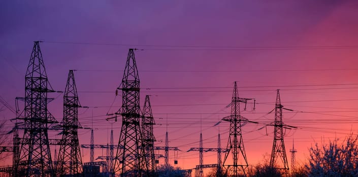 Panorama, silhouette of high voltage power lines against a colorful sky at sunrise or sunset. Download high quality photo