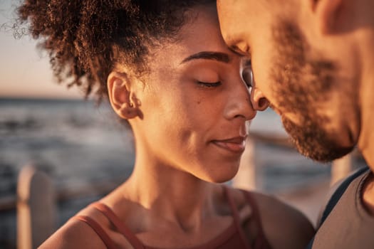 Black couple, hug and touching forehead embracing relationship, compassion or love and care by the beach. Happy man and woman with heads together smiling in happiness for support, trust or romance.