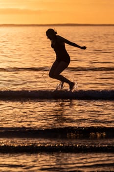 Silhouette of female swimmer having a splash in the Atlantic ocean in Ireland.