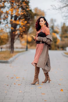 A woman walks outdoors in autumn, enjoys the autumn weather