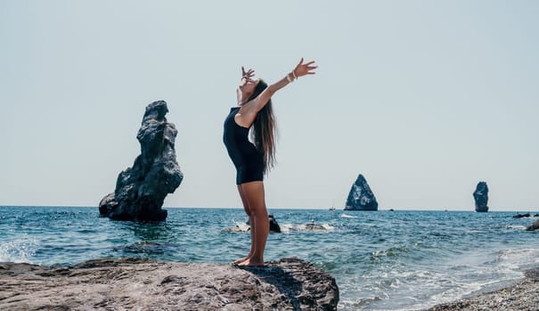 Woman travel sea. Young Happy woman in a long red dress posing on a beach near the sea on background of volcanic rocks, like in Iceland, sharing travel adventure journey