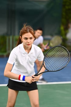 Focused female athlete with a racket waiting to receive ball during match. Sport, training and active life concept.