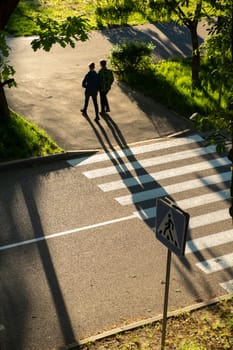 crosswalk with shadows of pedestrians. couple walking across the crosswalk at the junction street of city. Pedestrian safety. silhouettes of people crossing a crosswalk.