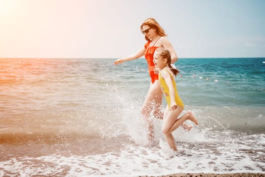 Happy loving family mother and daughter having fun together on the beach. Mum playing with her kid in holiday vacation next to the ocean - Family lifestyle and love concept.