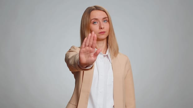 Business woman say No hold palm folded crossed hands in stop gesture, warning of finish, prohibited access, declining communication, body language, danger. Girl on gray background. People lifestyles