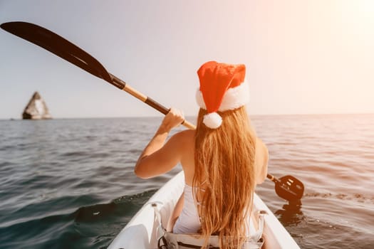 Woman in kayak back view. Happy young woman with long hair floating in transparent kayak on the crystal clear sea. Summer holiday vacation and cheerful female people relaxing having fun on the boat