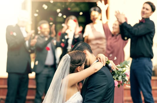 Bride, groom and kiss in wedding celebration with applause from family, friends or guests at the church. Man and woman couple kissing, hugging or embracing marriage in romance for happy relationship.