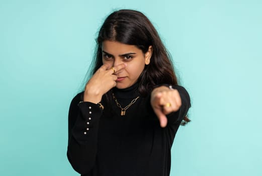 I am watching you. Young confident indian woman pointing at her eyes and camera, show I am watching you gesture, spying on someone. Pretty arabian hindu girl isolated alone on blue studio background