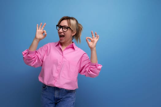 smart young blond businesswoman in a pink shirt and jeans is confident in her business on a studio background with copy space.