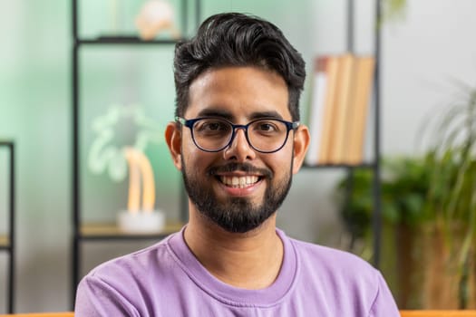 Portrait of happy calm indian man at home couch smiling friendly, glad expression looking away dreaming resting, relaxation feel satisfied concept good news, celebrate win. Hindu guy in living room
